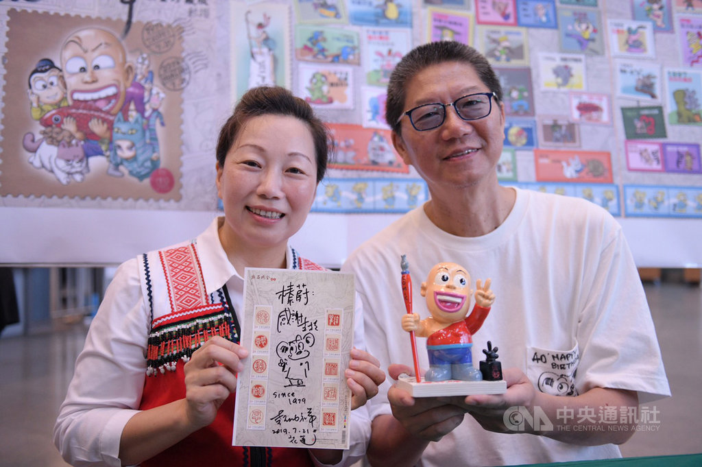 花蓮郵局推出「動漫大師敖幼祥40週年限量珍藏版郵摺」,21日在花蓮火車站設臨時郵局開賣,花蓮縣長徐榛蔚(左)化身書迷到場,漫畫大師敖幼祥(右)致贈編號0001珍藏版郵摺、大師兄公仔給徐榛蔚,並繪製漫畫插圖作為紀念。(花蓮縣政府提供)中央社記者李先鳳傳真 108年7月21日
