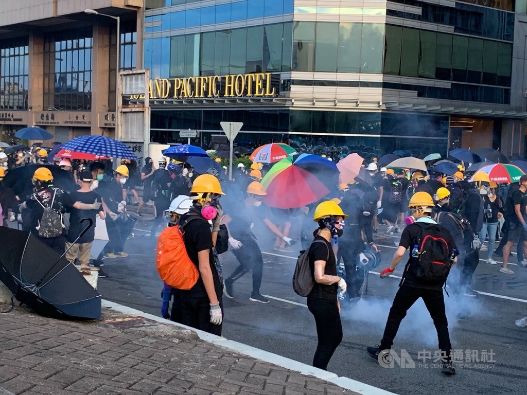 香港反送中自主遊行人士今天下午包圍中聯辦,港警晚間7時高舉黑旗,隨即施放催淚彈進行清場。圖為示威者熟練地拿水瓶澆熄催淚彈。中央社記者廖漢原香港攝 108年7月28日