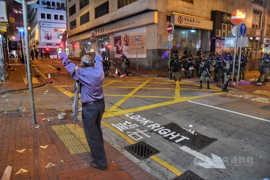 香港反送中活動28日持續延燒,港島市區猶如大型游擊戰場,大批警力晚間強勢驅離示威民眾,一名家住上環的市民深夜返家,看見鎮暴警察隨即高舉雙手,表明自己並非示威者。中央社記者王飛華香港攝 108年7月28日