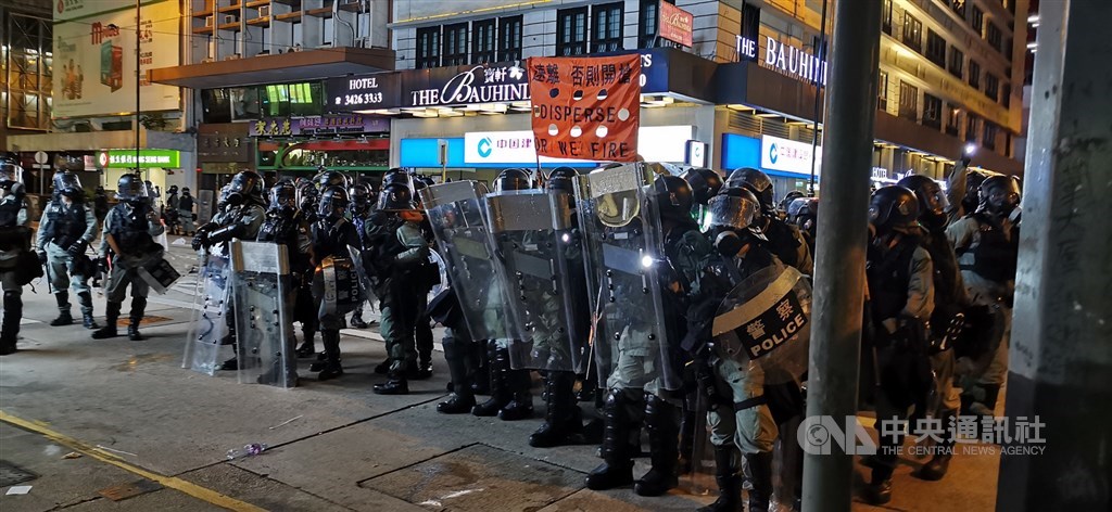 香港中環遮打花園追究警方用槍集會,演變為西環包圍中聯辦;港警晚間7時起清場,沿途狂射催淚彈意圖逼退示威者。圖為警方高舉開槍橙旗。中央社記者張謙香港攝 108年7月28日