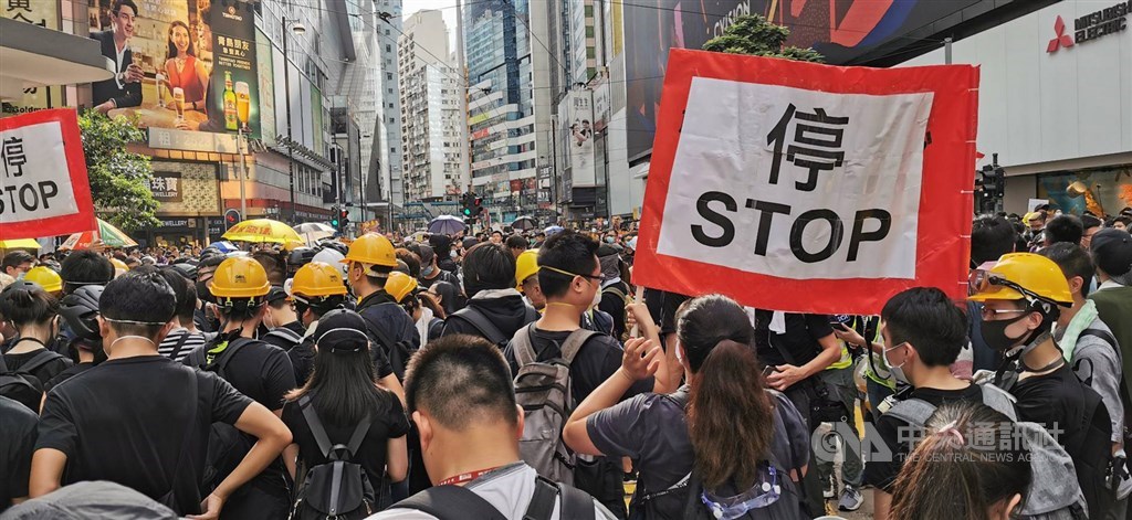 香港28日反送中「自發」遊行,示威者採取「突襲」路線,未往西行至中聯辦,反向東往銅鑼灣前進,港警未能預料,從中心地帶金鐘到政府總部的灣仔沿途未見警察維持秩序。圖為至銅鑼灣有示威者高舉「停」字布條指揮隊伍。中央社記者張謙香港攝 108年7月28日