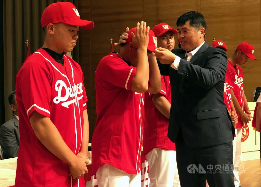 中職味全龍隊今年季中選秀選中南華大學棒球隊成員6人,1日在南華大學校內舉辦新秀加盟記者會,總教練葉君璋(前右)為加盟球員穿上球衣、戴上球帽。中央社記者黃國芳攝 108年8月1日