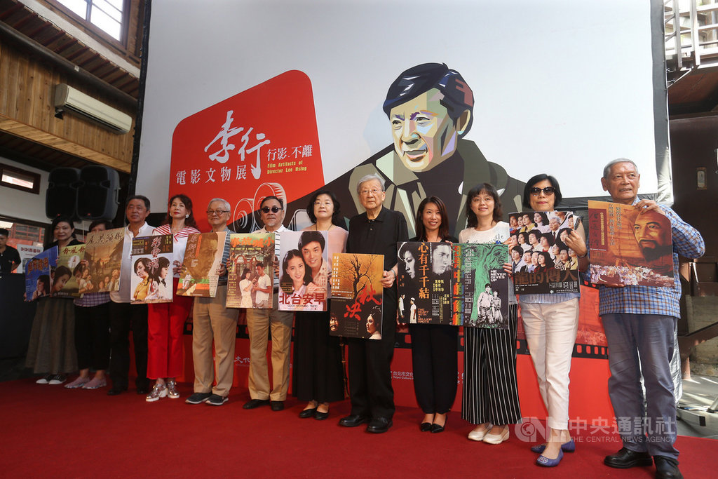 「行影‧不離─李行電影文物展」2日在台北市剝皮寮演藝廳舉行開幕記者會,資深導演李行(右5)與來賓們拿著電影海報合影留念。中央社記者徐肇昌攝 108年8月2日