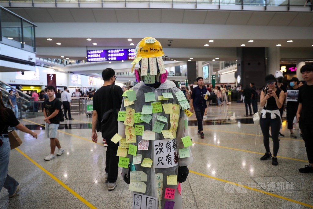香港國際機場9日有民眾發起反送中集會,下午4時左右現場推估已有逾千人參加,他們穿著黑衣、在入境大廳靜坐,還有人讓民眾直接在身上張貼各種支持標語,成為「人體連儂牆」。中央社記者吳家昇攝 108年8月9日