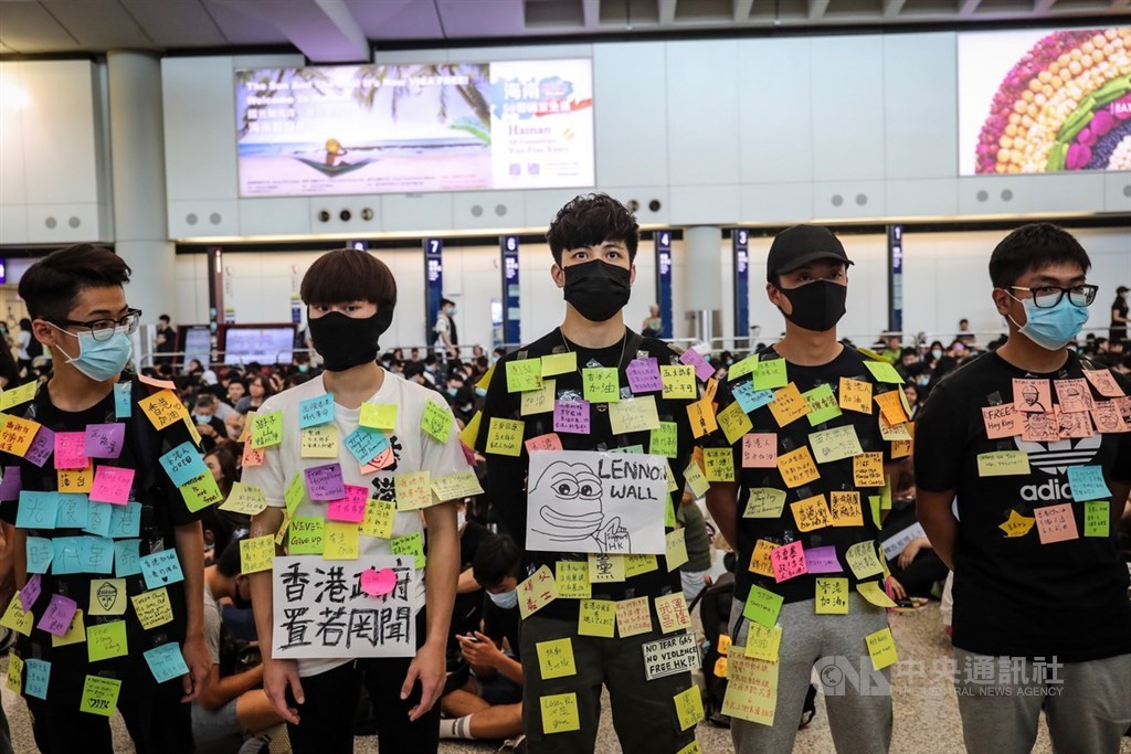 香港反送中運動持續延燒,9日在機場有民眾發起集會活動,下午4時許,推估已有逾千人穿著黑衣到場響應,有民眾更以自身當作「連儂牆」,讓民眾貼上標語。中央社記者吳家昇攝 108年8月9日