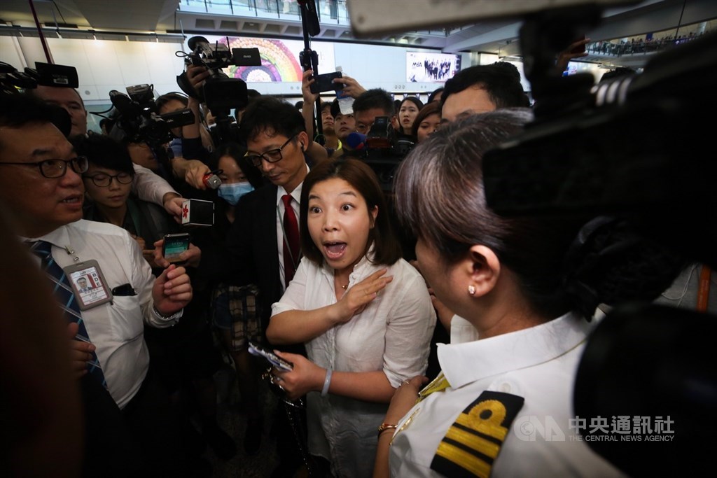 香港國際機場9日有民眾發起「反送中」集會,他們穿著黑衣在入境大廳靜坐表訴求,不過有一名女子到場表達反對示威者立場,隨即被帶離集會現場。中央社記者吳家昇攝 108年8月9日