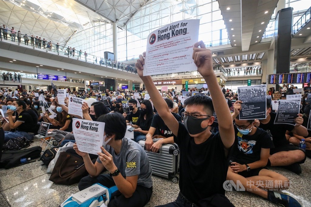 香港國際機場9日有「反送中」集會,部分參加集會民眾在背部貼上不同語言的標語並向旅客展示,又向入境旅客派發不同語言的反修例小冊子和貼紙等,以行動表達立場及訴求。中央社記者吳家昇攝 108年8月9日