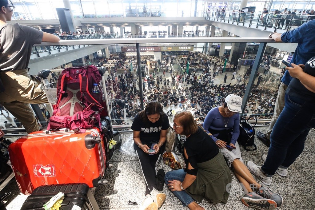 香港國際機場9日有民眾發起「反送中」集會活動,大批黑衣人在入境大廳和平靜坐,有參與者向媒體表示,會盡量以不騷擾旅客方式,向旅客傳達反修例運動訴求。中央社記者吳家昇攝 108年8月9日