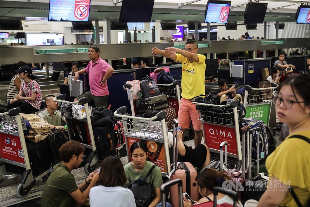 香港機場12日下午近4時宣布取消所有航班,所有登機服務即時暫停,許多旅客無法辦理手續,只能帶著行李席地而坐。中央社記者吳家昇攝 108年8月12日
