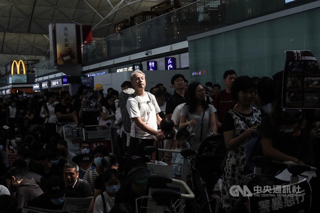 香港「反送中」抗爭11日遭警方空前強勢鎮壓,一名示威女子遭射傷右眼,引發黑衫軍強烈憤慨,12日中午1時號召支持者全面罷工,百萬人塞爆機場,旅客被擠在抗爭人群中。中央社記者吳家昇攝 108年8月12日