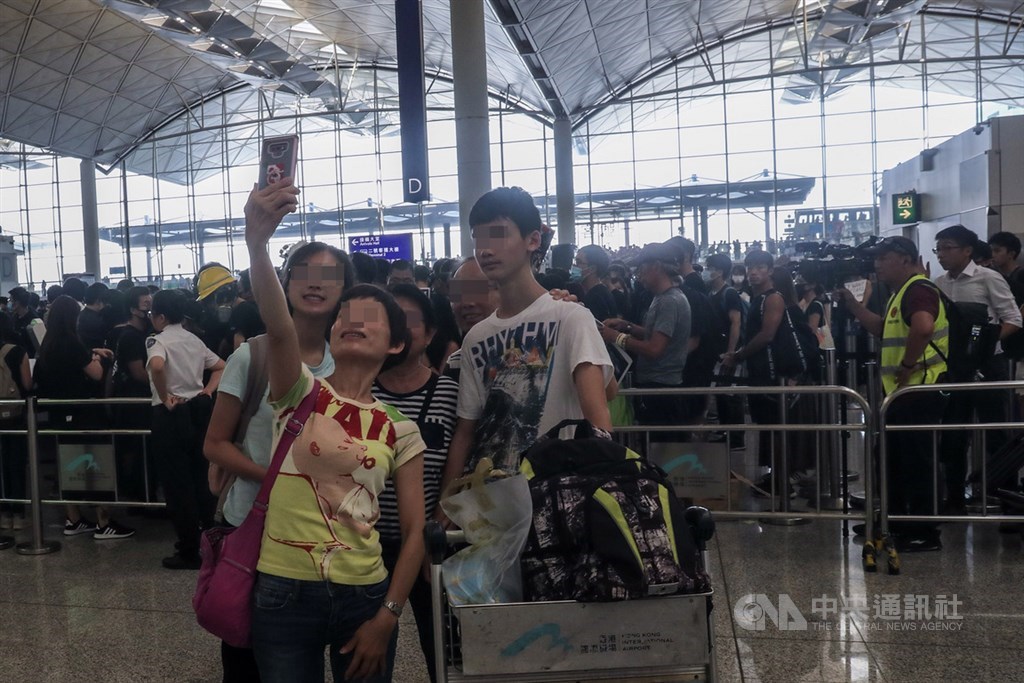 香港「反送中」抗爭11日遭警方空前強勢鎮壓,一名示威女子遭射傷右眼,引發黑衫軍強烈憤慨,12日中午1時號召支持者全面罷工聚集機場,有旅客在機場自拍留影。中央社記者吳家昇攝 108年8月12日