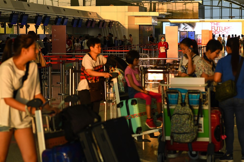 香港機場13日一早恢復作業,乘客等候辦理登機手續。(法新社提供)