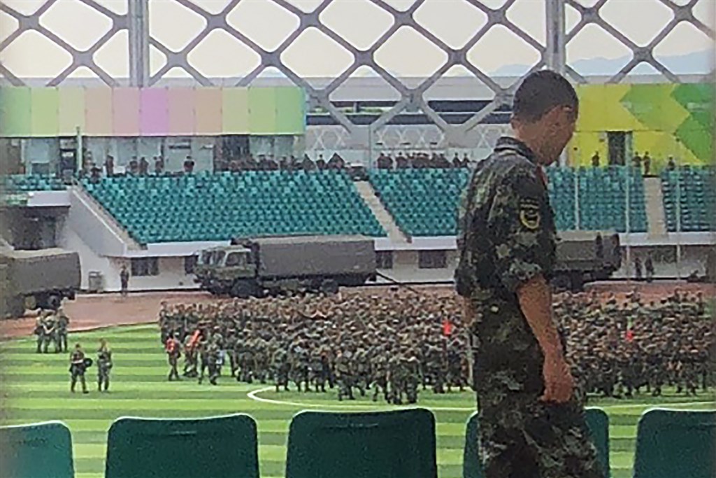 一名法新社記者目擊,數千名中國軍事人員15日在與香港毗鄰的深圳市一座體育館揮舞紅色旗幟進行操練。(法新社提供)