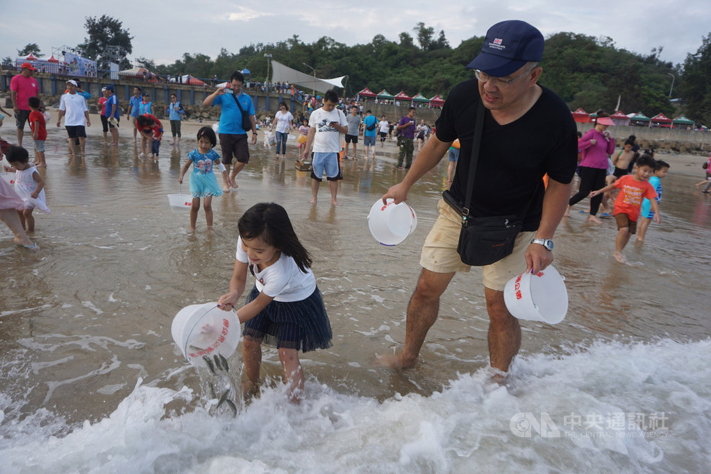 2019金湖海灘花蛤季活動18日進入第2天,重頭戲的「千人魚苗放流」吸引大批民眾扶老攜幼參加,小朋友開心體驗放流魚兒。中央社記者黃慧敏攝 108年8月18日