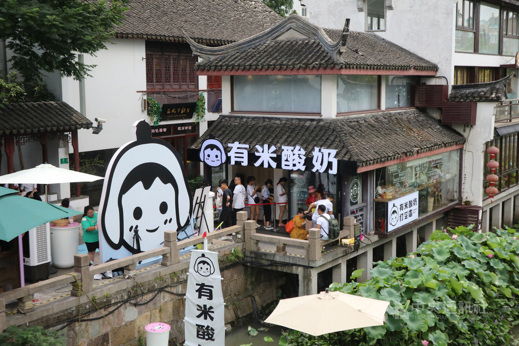 中國希冀以內需拉動經濟,消費升級的風潮也吹至酸奶(優格)領域。上海有業者就將酸奶做成手搖飲料,於7月底在七寶老街開出「有米酸奶」,短短一個月就成了年輕人追捧的網紅店。圖為門市外觀與排隊人潮。中央社記者陳家倫上海攝 108年8月21日