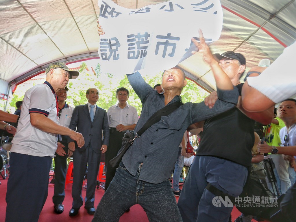 台北市長柯文哲(後左3)23日在台北出席八二三砲戰紀念音樂饗宴,遭到抗議人士拉標語抗議,維安人員上前將人帶走。中央社記者徐肇昌攝 108年8月23日