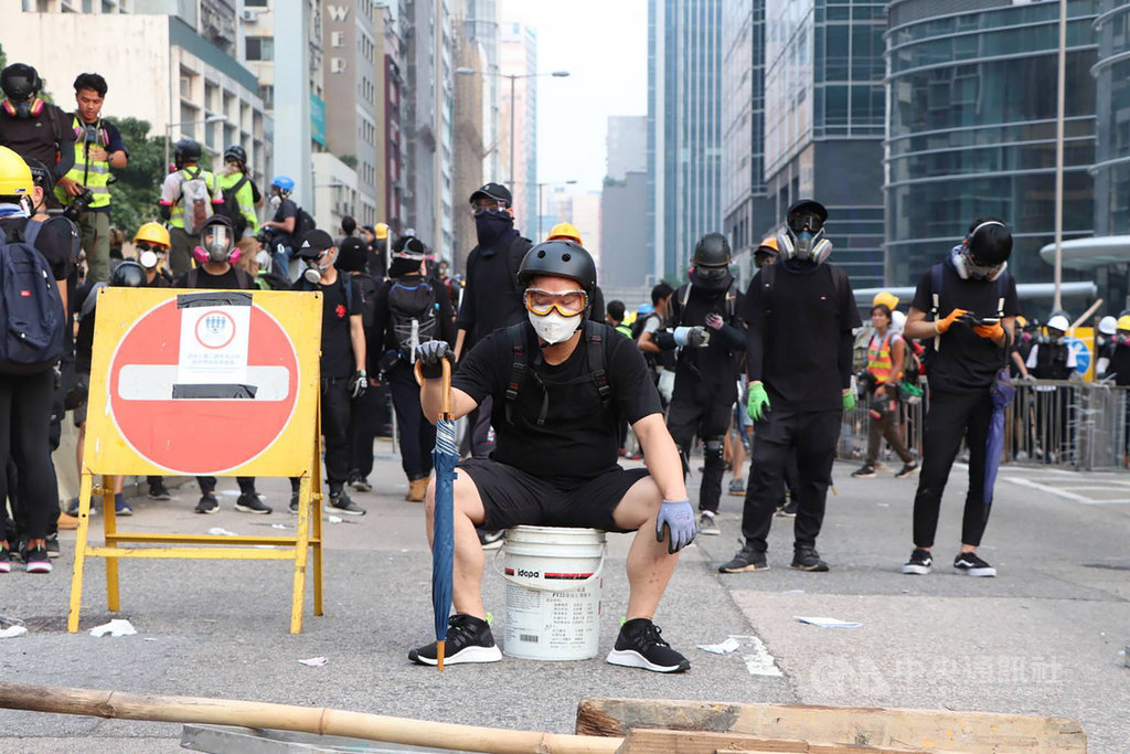香港「反送中」示威者24日下午在九龍觀塘遊行結束後,轉進包圍附近牛頭角警署;警方發射多輪催淚彈和胡椒球彈驅離,大批抗議者走避,有人眼部受傷送醫。圖為示威者防線前「沈思」。中央社記者張謙香港攝 108年8月24日