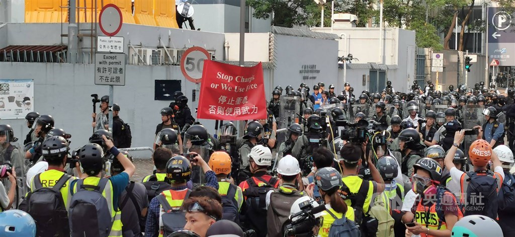 香港「反送中」示威者24日在九龍觀塘舉行遊行。結束後,大部分抗議人士轉進包圍附近的牛頭角警署;4時30分左右,警方向示威者舉起紅旗,警告不要衝擊,否則使用武力。中央社記者張謙香港攝 108年8月24日