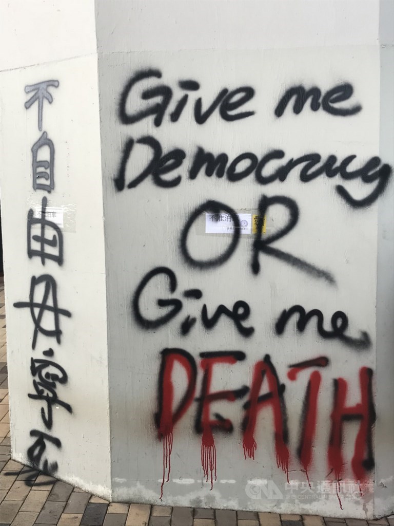 香港「反送中」示威者在海濱道旁的橋墩噴上「give me democracy, or give me dead.」 該標語也曾出現在1989年的天安門學運中。中央社記者沈朋達香港攝 108年8月24日