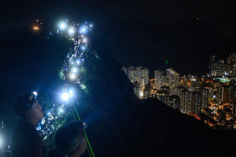 香港23日晚間出現「香港之路」活動,民眾自發登上獅子山山頂,以手機燈光照亮山脊線。(法新社提供)