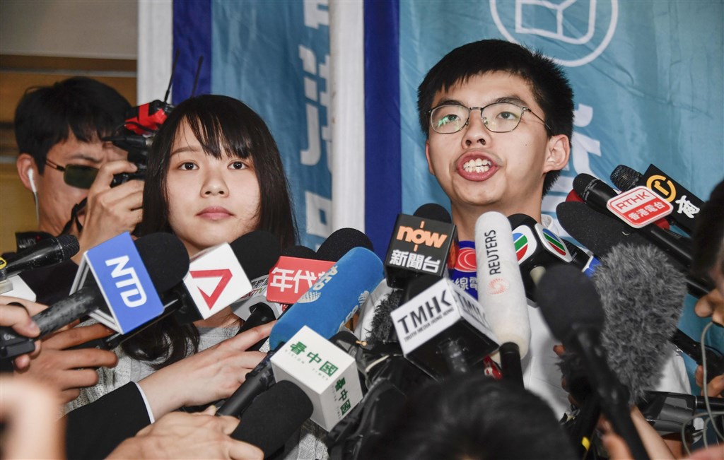香港眾志祕書長黃之鋒(右)和成員周庭30日上午突然被捕,下午交保。(共同社提供)