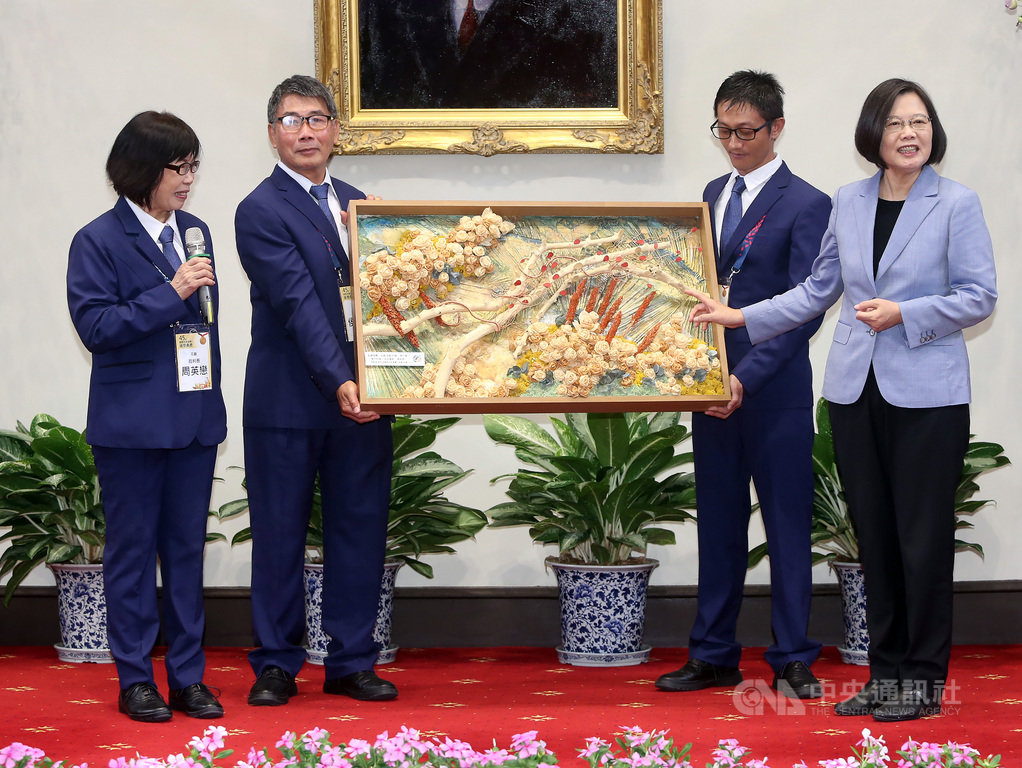 總統蔡英文(右)4日上午在總統府接見第45屆國際技能競賽代表團,代表團送給蔡總統結合花藝、木藝、漆藝、以台灣山川百岳為背景及用台灣檜木刨成一朵朵玫瑰的畫作。中央社記者鄭傑文攝 108年9月4日