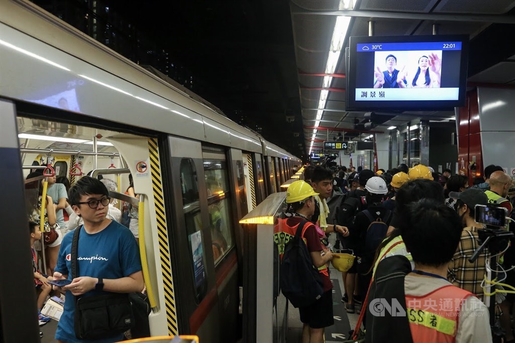 示威者在九龍灣地鐵站月台討論後續行動,引起列車上的民眾注目。
