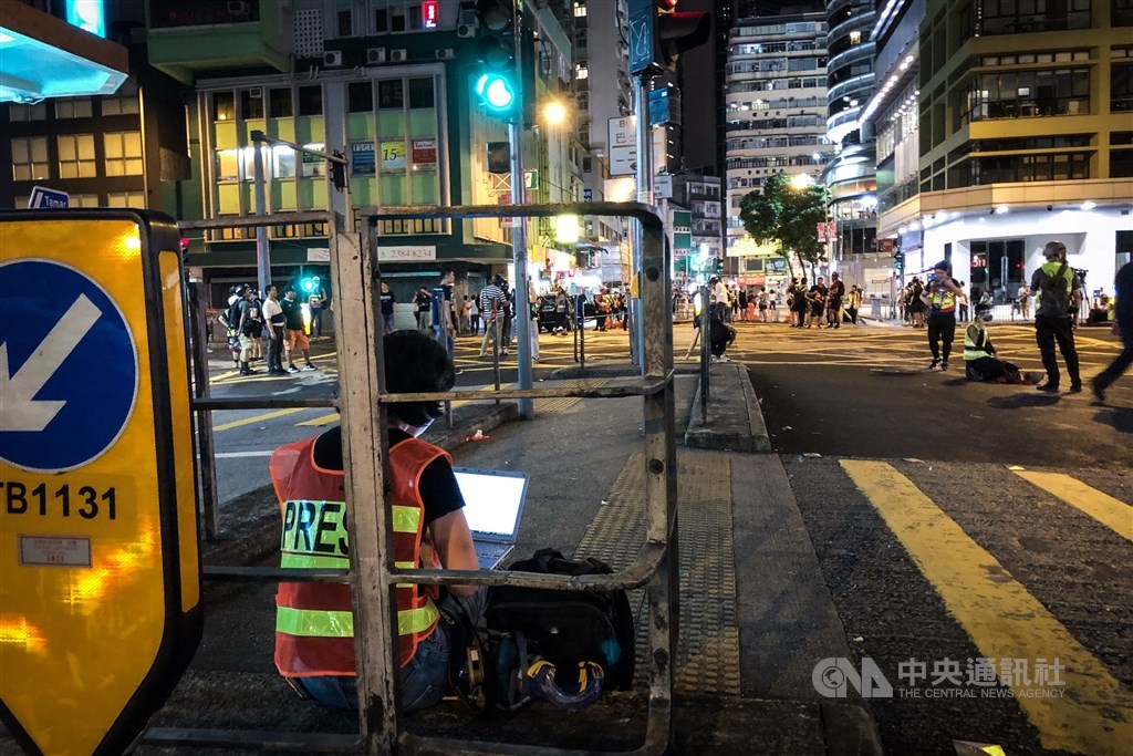 在抗爭現場中席地而坐發稿的文字記者。