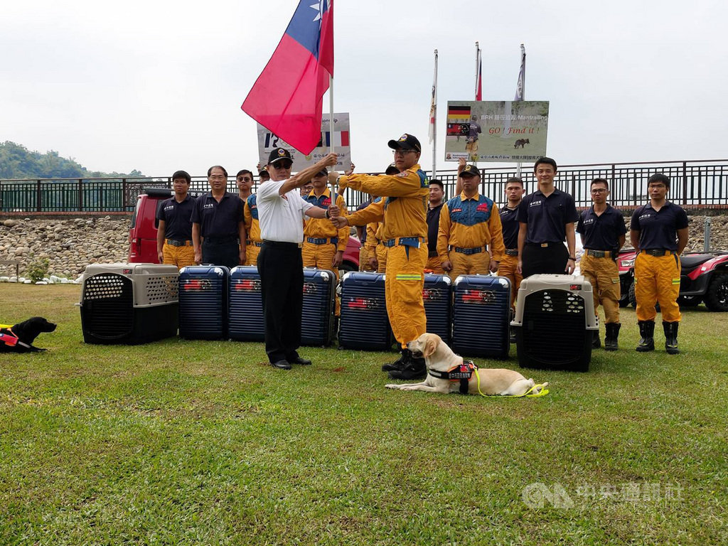 台中市消防局特搜大隊搜救犬隊共5人2犬將代表台灣出征「2019法國搜救犬世界盃」,13日準備搭機出發,消防局長曾進財(前左)親自授旗給搜救犬隊,預祝旗開得勝。(台中市消防局提供)中央社記者趙麗妍傳真 108年9月13日