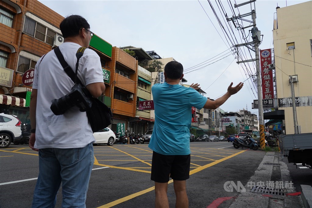 住戶比劃著說明當年大樓傾倒的狀況。(中央社記者孫仲達攝)
