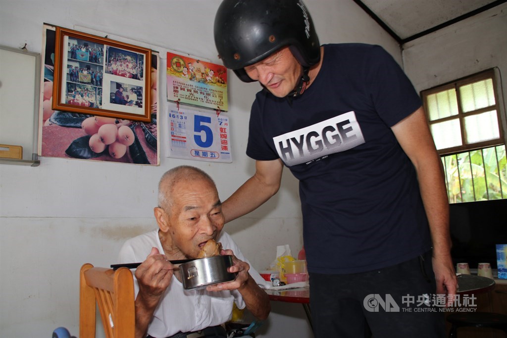 九二一地震改變機車行老闆邱慶禧的一生,決定要做老人送餐。圖為接受南投縣生活重建協會照顧20年、85歲獨居的林阿公(左)看著菜色直說「讚」,邱慶禧(右)順道勸他少喝點酒。中央社記者蕭博陽南投縣攝 108年9月18日