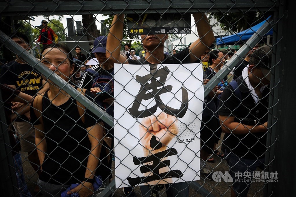 印度中國專家謝鋼撰文指出,中國在香港加強「一國」而非「兩制」引發香港人強烈反對。圖為8月11日維園反送中集會,民眾手持印有「民主」的標語表達訴求。(中央社檔案照片)