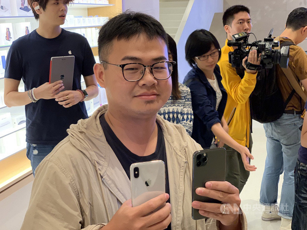 iPhone 11系列新機20日在台灣開賣,12年資深果粉許先生從凌晨4時左右到蘋果直營店Apple信義A13排隊,搶得頭香,並展示目前使用的白色iPhone X(左)和20日購買的夜幕綠色iPhone 11 Pro Max(右)。中央社記者吳家豪攝 108年9月20日