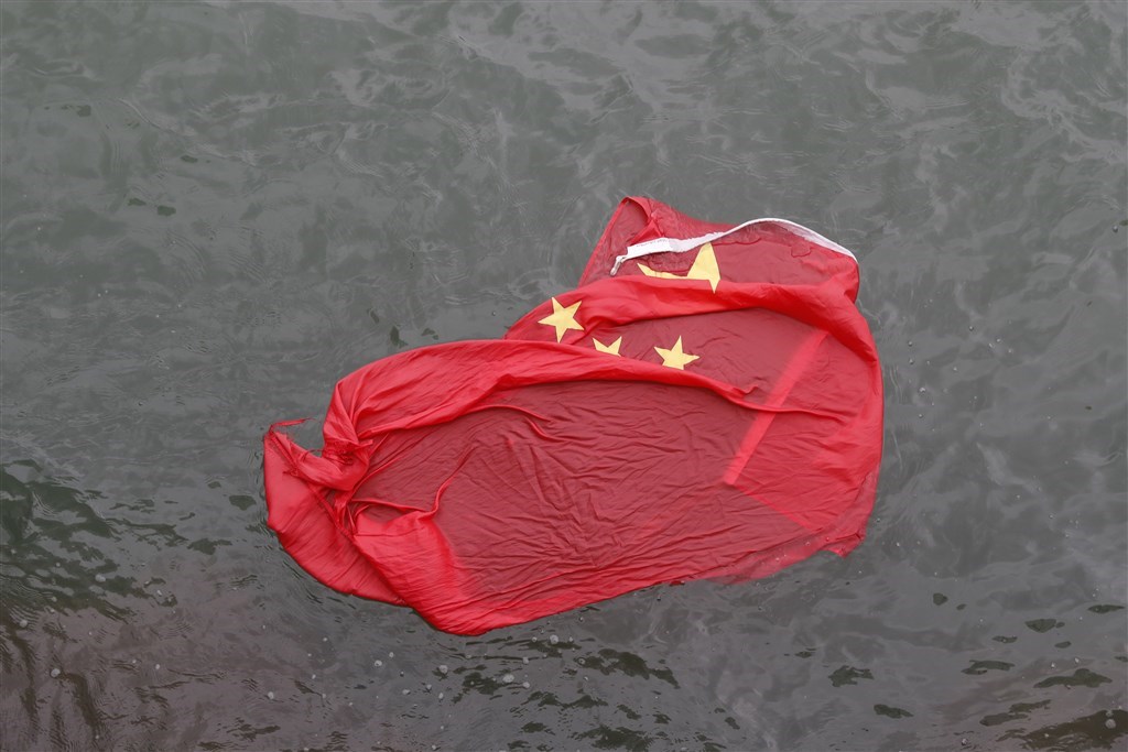 8月3日的旺角遊行中,一群蒙面示威者把尖沙咀海港城旗杆上的五星旗降下,丟入海中。(美聯社)