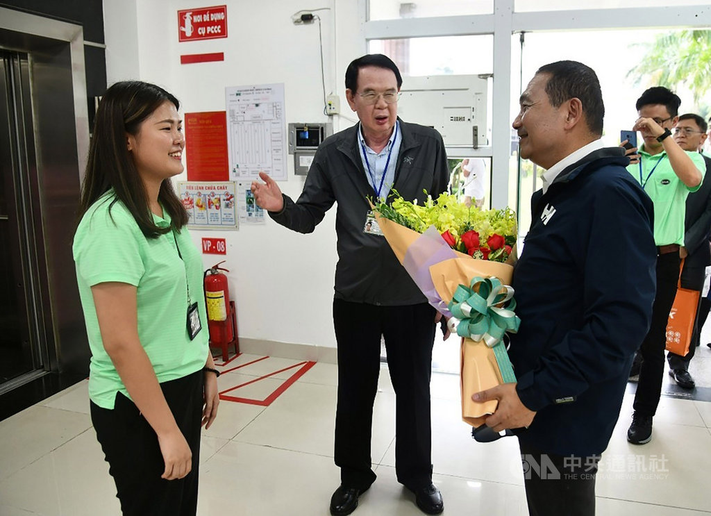 新北市長侯友宜(右)23日由儒鴻企業董事長洪鎮海(中)陪同,參觀越南同奈省的仁澤成衣廠,台灣新住民第二代廠長Rita(左)獻花歡迎。(新北市政府新聞局提供)中央社河內傳真 108年9月23日
