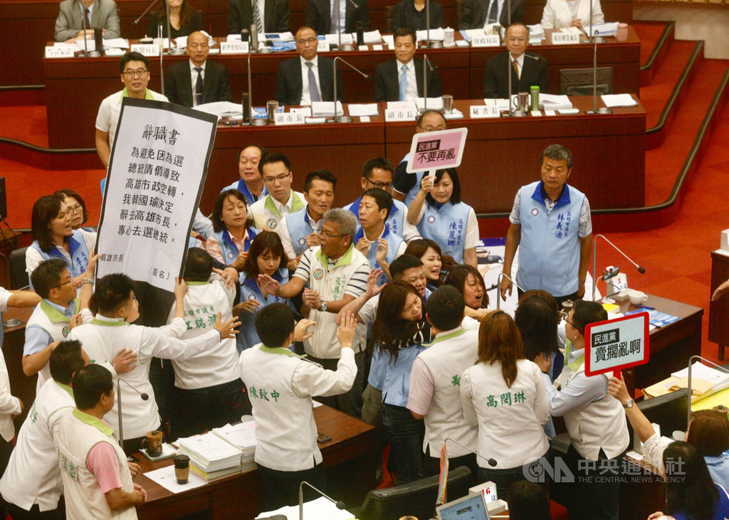 高雄市議會26日進行市政施政報告與質詢,民進黨議員鄭孟洳送市長韓國瑜(後排右4)「辭職書」促韓辭職再去選舉,國民黨議員也舉出「民進黨不要再亂」的標語,雙方爆發推擠衝突。中央社記者董俊志攝 108年9月26日