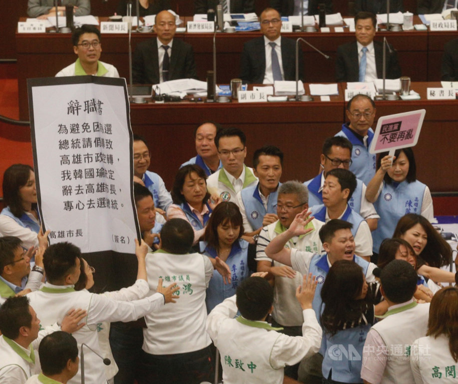 高雄市議會26日進行市政施政報告與質詢,民進黨議員鄭孟洳拿出「辭職書」要給高雄市長韓國瑜(後排右3),但被國民黨議員包圍擋下,雙方爆發推擠衝突。中央社記者董俊志攝 108年9月26日