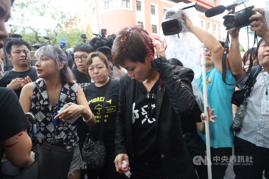 多個公民團體共同發起「929台港大遊行-撐港反極權」活動,29日下午3時在立法院旁登場,香港歌手何韻詩(前中)行前受訪時,突遭一名戴頭盔、蒙面的不明人士從後方潑紅漆。中央社記者裴禛攝 108年9月29日