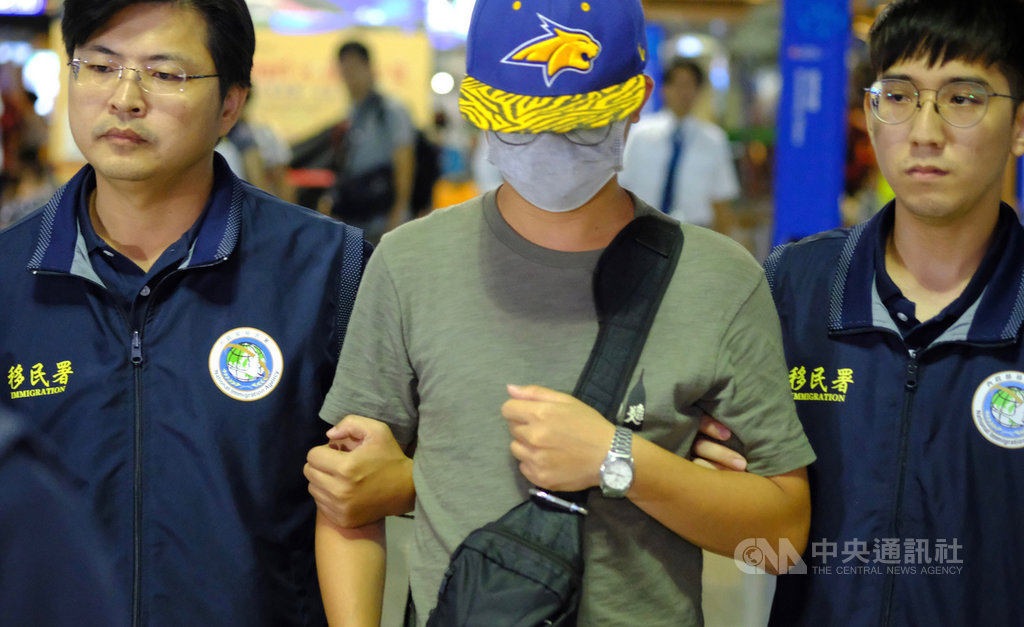 30歲中國籍李姓男子(中)涉嫌撕毀台大校內連儂牆所貼的反送中海報,被依法強制出境,晚間在移民署人員陪同下搭機離境。中央社記者邱俊欽桃園機場攝 108年10月8日