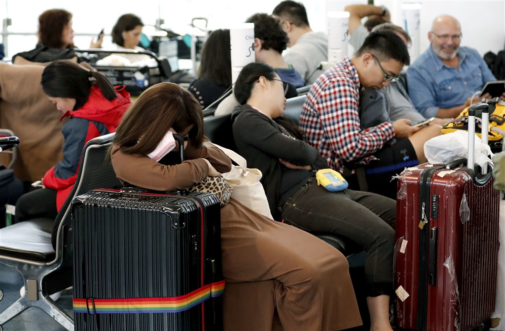 颱風哈吉貝襲日本,大多數航班被取消,旅客在東京羽田機場國際航站休憩。(共同社提供)