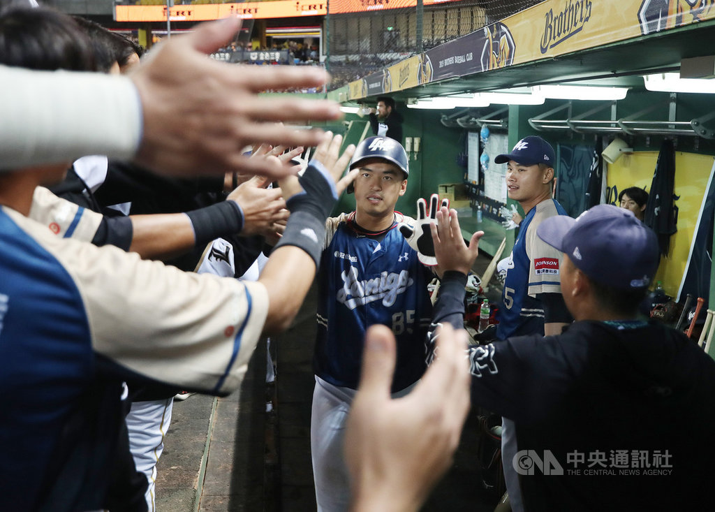 2019中職總冠軍賽15日在台中洲際球場進行第3戰,2局上,桃猿朱育賢(中)敲出安打上壘,再靠著隊友推進,回到本壘得分,在休息區與隊友擊掌致意。中央社記者張新偉攝 108年10月15日