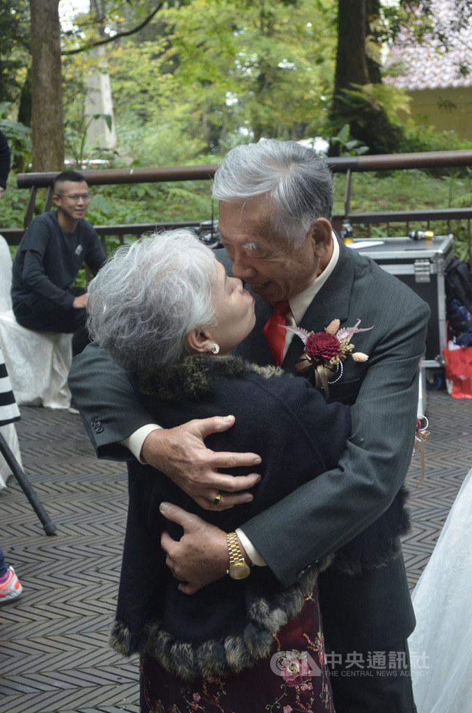 已經結縭43年的饒舜濱(右)與李素月(左)20日參加「阿里山神木下婚禮」活動,在結婚儀式完成後,司儀要求接吻時,他們不像年輕人直接擁吻,但饒舜濱仍把老婆抱得緊緊的。中央社記者蔡智明攝 108年10月20日