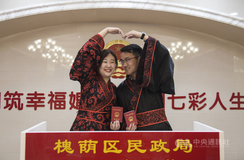 中國人大21日表示,對法定婚齡暫不做修改,消息傳出後,獲得多數未婚網友叫好,並指問題在晚不在早,他們沒錢結婚買房生小孩。圖為3月8日,山東濟南一對新人穿漢服前往民政局領結婚證。(中新社提供)中央社 108年10月22日