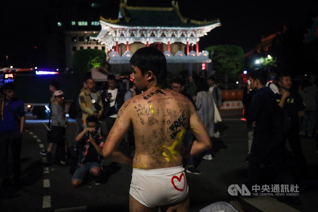 第17屆台灣同志遊行26日在台北登場,有遊行民眾僅著內褲,讓路過民眾在身上寫下支持香港反送中言論,成了一名「連儂人」。中央社記者吳家昇攝 108年10月26日
