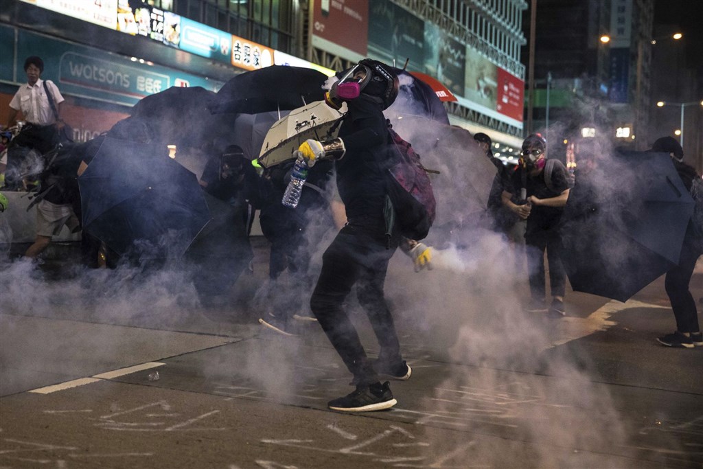 香港「反送中」網友27日下午發起追究警察暴力集會遭警方強力驅散後,晚間警民雙方集中在旺角彌敦道攻防,防暴警察多次推進驅散並發射多枚催淚彈。(法新社提供)