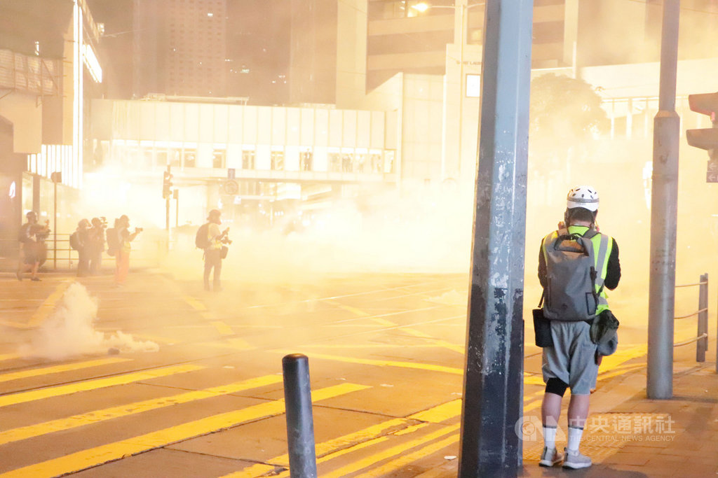 香港「反送中」網友趁著31日萬聖節之際發起集會遊行,許多人不顧禁蒙面法,戴著面具上街。圖為警方晚間10時左右在蘭桂坊附近發射催淚彈驅散示威者。中央社記者張謙香港攝 108年10月31日