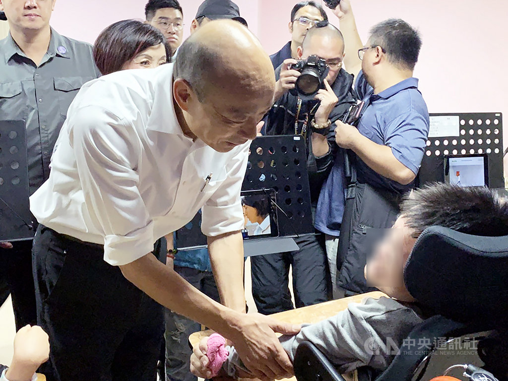 國民黨總統參選人韓國瑜(左)7日前往新竹縣竹東鎮世光教養院,看到因身體障礙而無法行動的院生時,他握著院生的手,為院生加油。中央社記者郭宣彣攝 108年11月7日