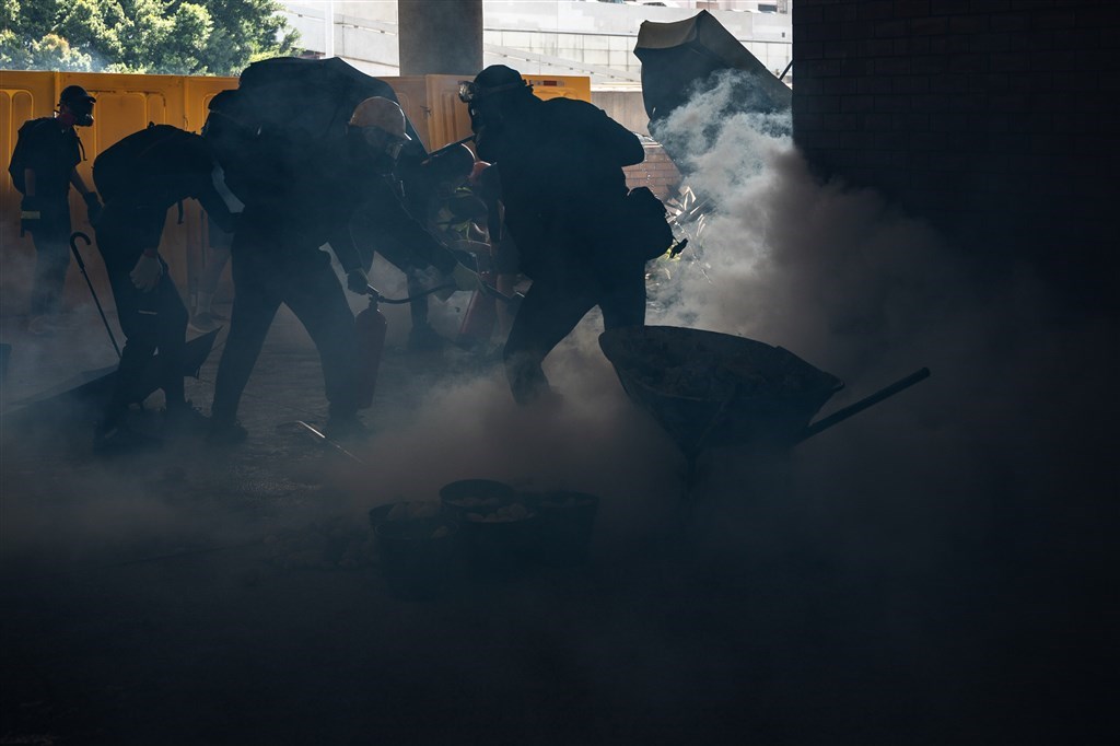 香港反送中群眾11日發起「三罷」活動,防暴警察進入香港中文大學和理工大學校園追捕黑衣示威者,並發射催淚彈。圖為理工大學學生在警方施放催淚彈後,使用滅火器撲滅。(法新社提供)