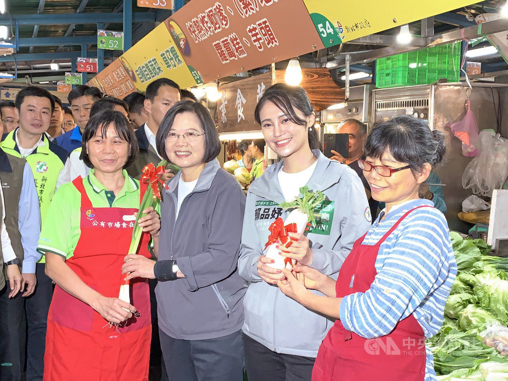 總統蔡英文(右3)13日在新北市汐止區陪同民進黨籍立委參選人賴品妤(右2)到黃昏市場拜票,有攤商送上象徵好彩頭的蘿蔔與祝福「凍蒜」的蒜苗。中央社記者葉臻攝 108年11月13日