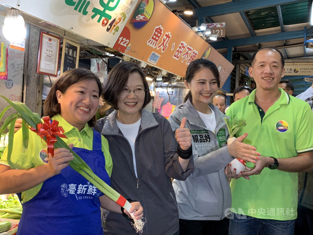 總統蔡英文(左2)13日在新北市汐止區陪同民進黨籍立委參選人賴品妤(右2)到黃昏市場拜票,有熱情攤商送上蘿蔔與蒜苗,祝福「凍蒜」。中央社記者葉臻攝 108年11月13日